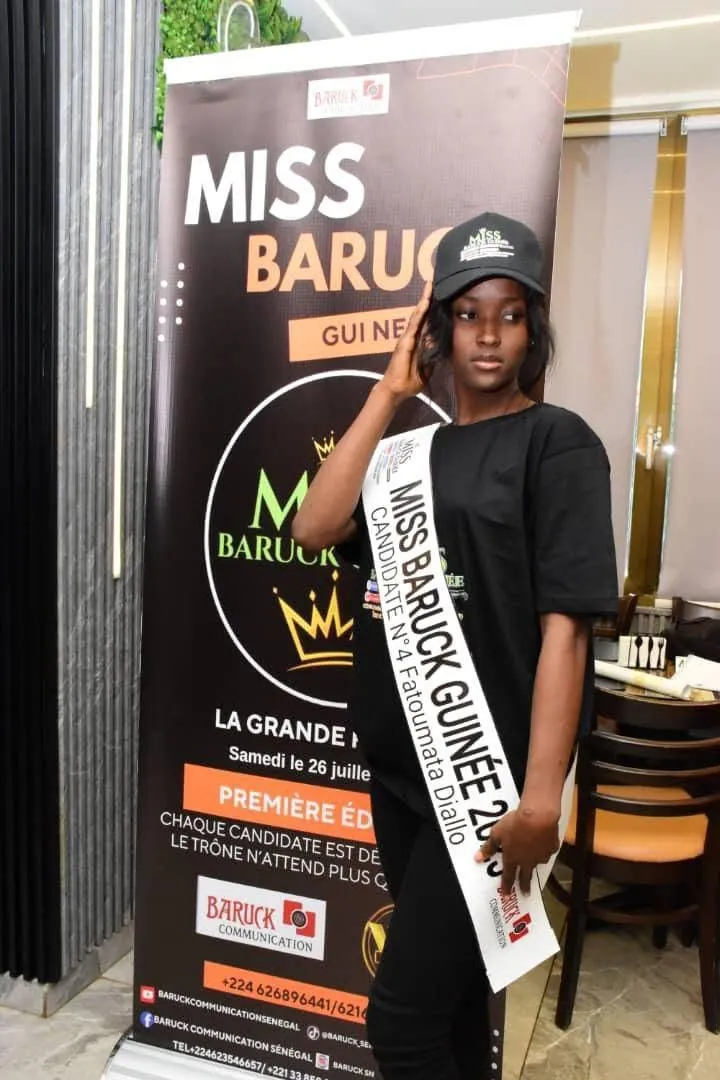 Une candidate en écharpe du concours, devant l’affiche de la grande finale