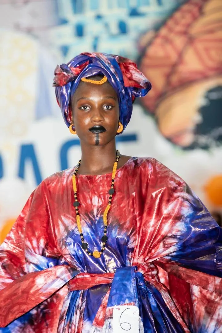 Passage sur le podium en tenue bleue et rouge avec foulard de tête assorti