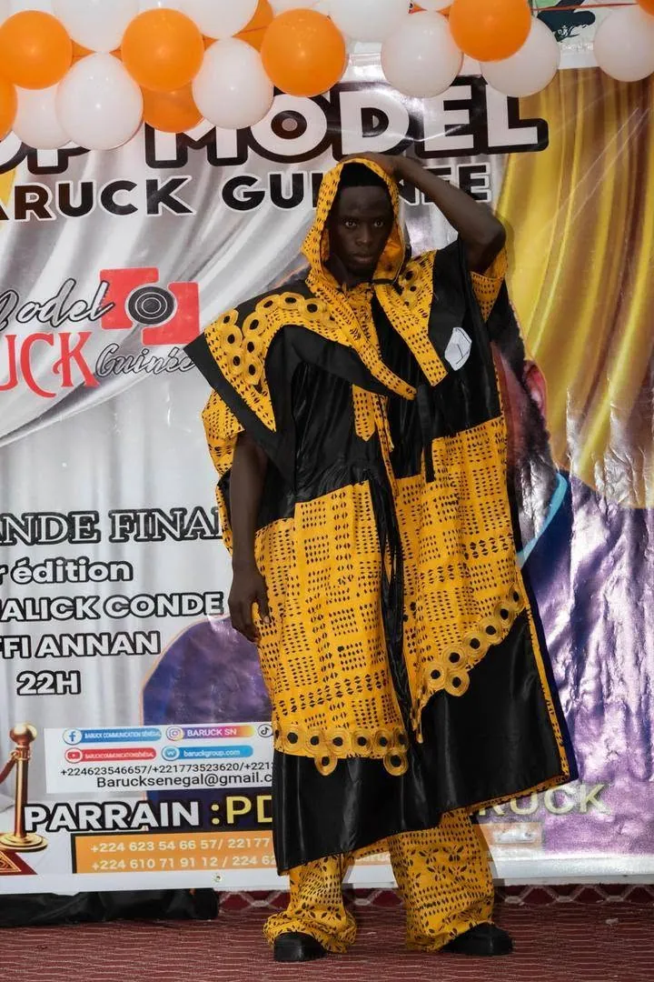 Passage sur le podium en boubou jaune et noir devant l’affiche de la finale