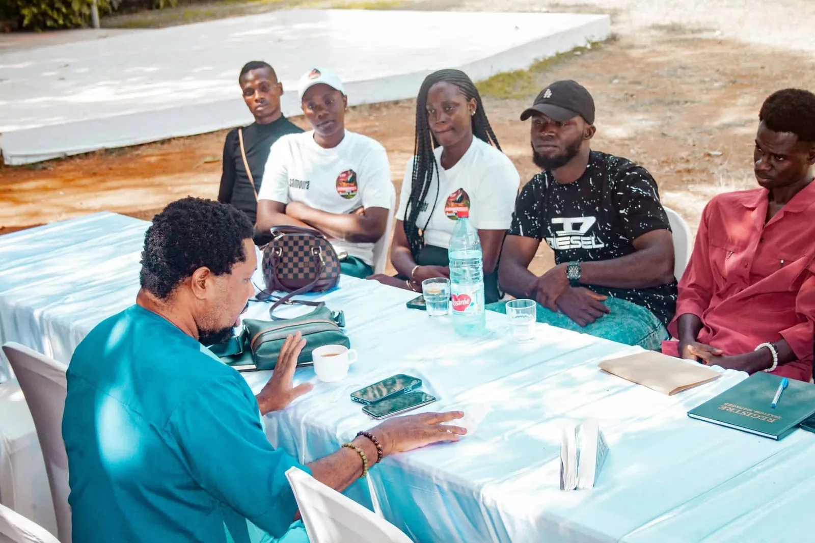 Les candidats inscrits assis autour de la grande table, certains en tee-shirt blanc floqué