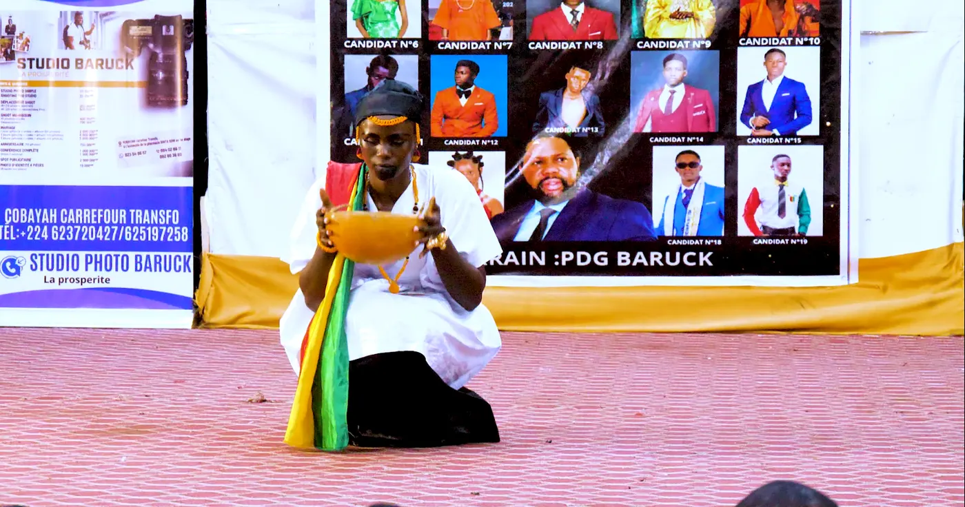 Le candidat n°5 agenouillé en boubou blanc, un drapeau posé au sol