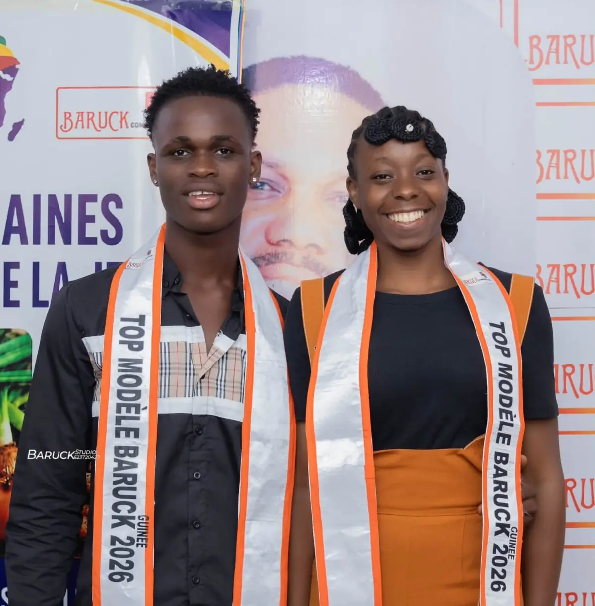 Les deux lauréats, écharpe Top Modèle Baruck Guinée 2026 sur les épaules, devant le photocall du concours