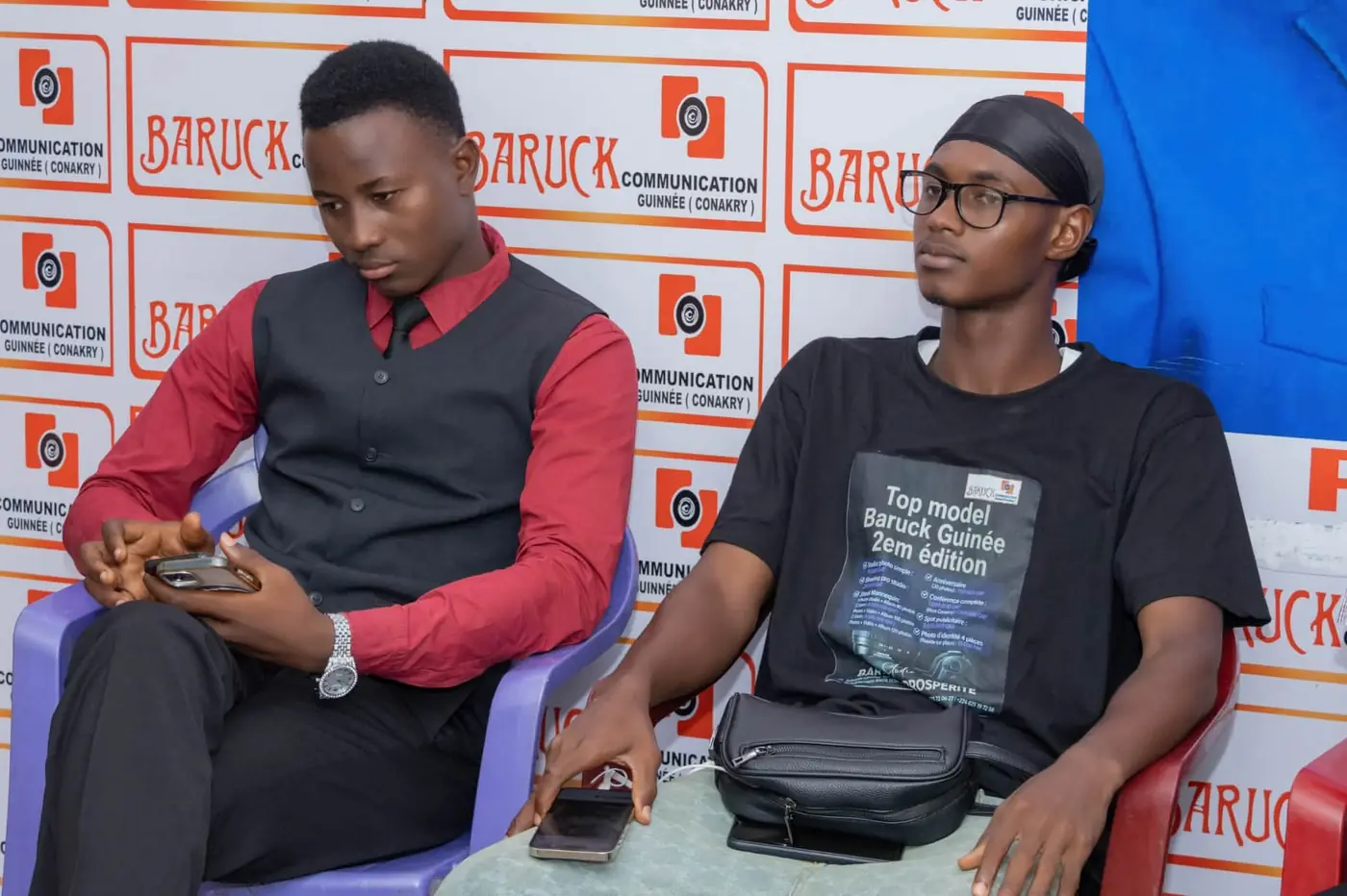 Deux candidats assis, l’un portant le tee-shirt de la deuxième édition du Top Modèle Baruck Guinée